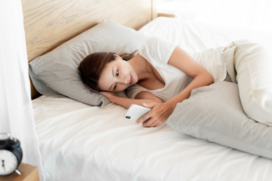 一位年轻女性躺在床上使用手机