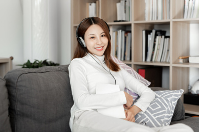 一位年轻女性正沙发上听音乐看书