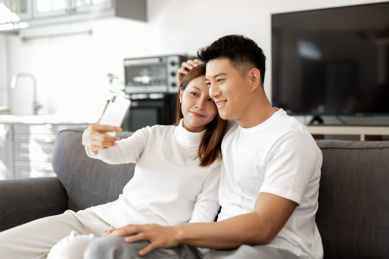 一对情侣正在沙发上使用手机拍照和自拍