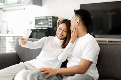 一对情侣正在沙发上使用手机拍照和自拍