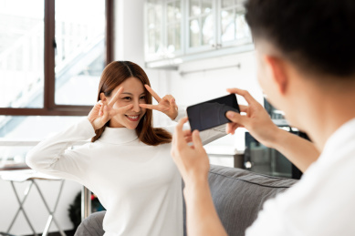 一对情侣正在沙发上使用手机拍照和自拍