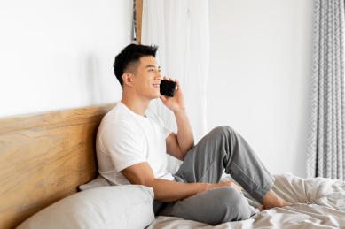 一个年轻的男性正在床上打电话