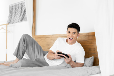 一位年轻的男性正在床上使用手机