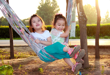 两个小女孩开心的坐在吊床上
