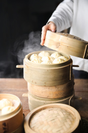 厨师抬起笼屉露出刚出炉热腾腾的包子