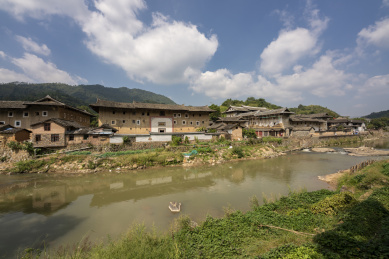 蓝天白云下河岸边的菜地及对岸的土楼群，中国福建永定