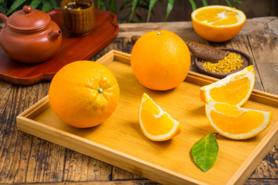 竹盘上放着完整的脐橙和一些切开的脐橙