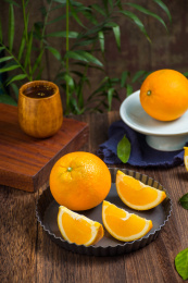 一个完整的脐橙和切开的三小块脐橙放在果盘中