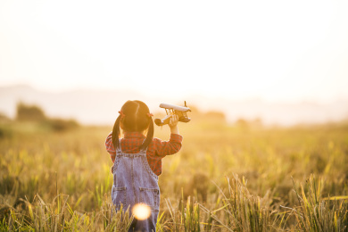 女孩子拿着模型飞机在田野玩耍