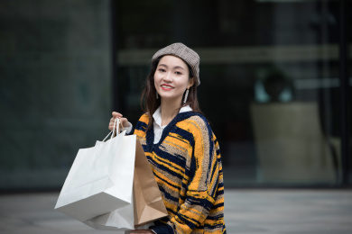 在商场门口提着购物袋的年轻女性