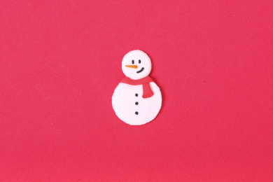 红色海绵纸上摆放彩色粘土捏制的披着红色围巾的雪人