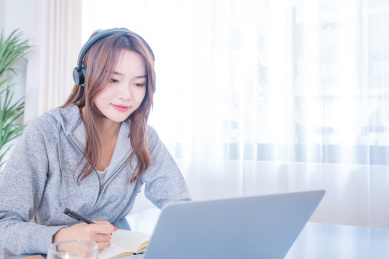 一名年轻的亚洲女子在坐在餐厅一边吃早餐一边