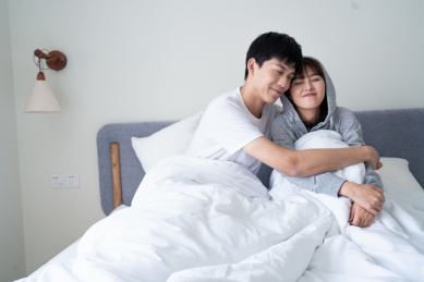 一对年轻的亚洲情侣在房间卧室内，甜蜜的拥抱