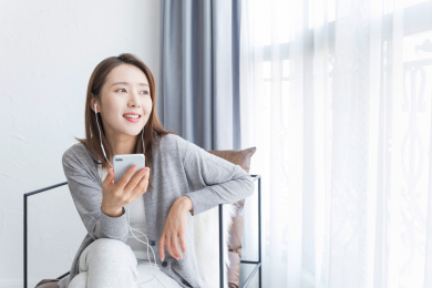 一名年轻女性坐在窗边跟别人打电话沟通