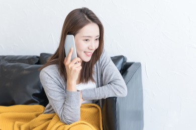 一名年轻女性坐在沙发上打电话