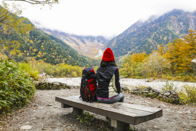 一个手拿登山杖坐在山谷河边的女性徒步旅行者