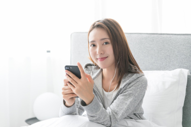 一名年轻女性坐在床上看手机