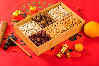  摆在红色背景上的装有坚果的果盘和对联红包