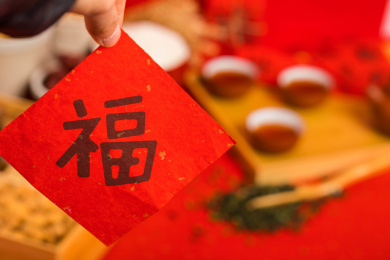 手拿着对联福字，背景是年货食品