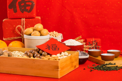 果盒上放着对联福字，旁边还摆着很多年货食品