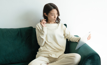 一名年轻女性在家里的客厅坐在沙发上玩平板电脑