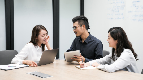 三名年轻商务人士在办公室对着笔记本电脑开会讨论