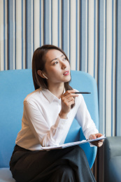 一位职场女性手拿文件夹坐在办公室思考