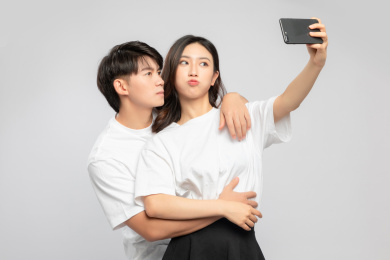  灰色背景里，正在自拍的亚洲年轻情侣