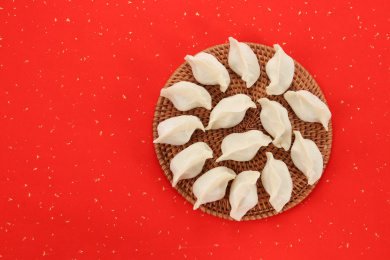 一盘未煮熟的饺子在红色背景上