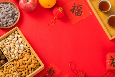 装有坚果的果盒和水果及对联放在红色背景上