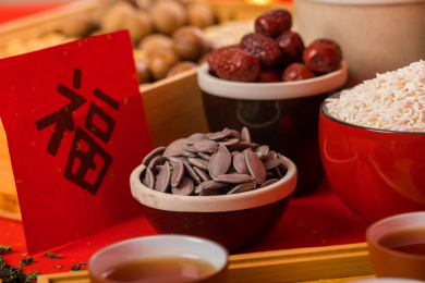 装有坚果的果盒和碗装有的食品及茶具一同放在红色背景上