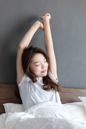 卧室里一名年轻女性在床上伸懒腰