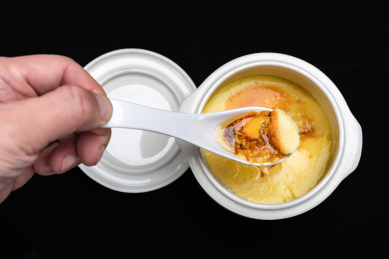 一只手拿白色汤勺盛装白陶瓷炖盅里的鸡蛋糕