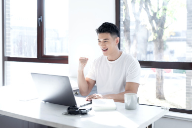 清晨坐在窗边使用移动设备的一位亚洲年轻男性