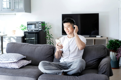 坐在沙发上享受音乐的一位亚洲年轻男性