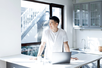 清晨站在窗边的一位亚洲年轻男性