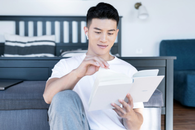 清晨在卧室读书的一位亚洲年轻男性