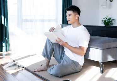 清晨在卧室读书的一位亚洲年轻男性