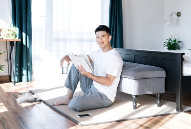 清晨在卧室读书的一位亚洲年轻男性