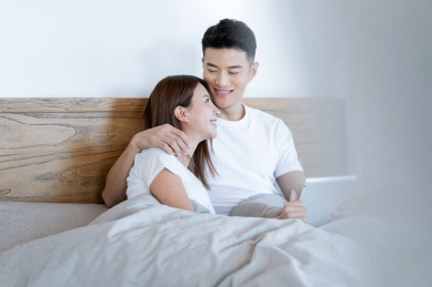 清晨在卧室中使用移动设备的一对亚洲年轻情侣