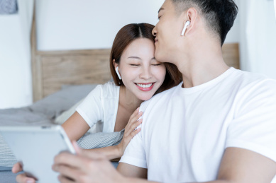 清晨在卧室中使用移动设备的一对亚洲年轻情侣