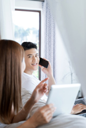 清晨在卧室中使用移动设备的一对亚洲年轻情侣