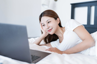 清晨在卧室中使用移动设备的一个亚洲年轻女性