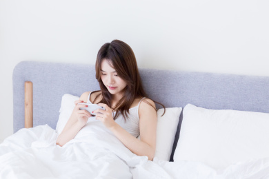 坐在床用手机玩游戏的中国女孩