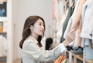 美女在商场内选购衣服，手拿袖子