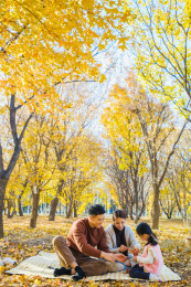 一家三口坐在秋天的树林里