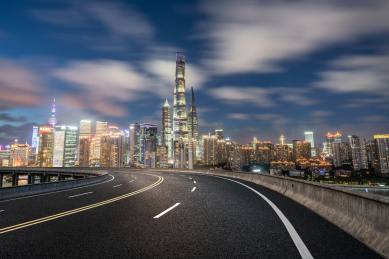 陆家嘴夜景前一条弯曲的高架柏油路穿过，中国上海