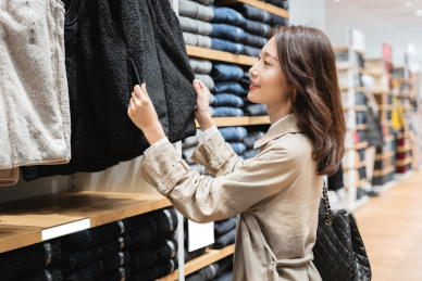 年轻都市女青年在服装店内选购冬季服装