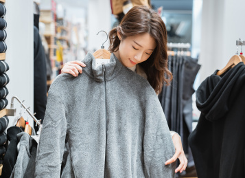 年轻都市女青年在服装店内选购冬季服装