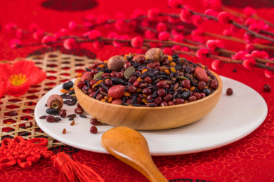 用木盘装着的新鲜五谷食材黑米红豆粥放在红色背景上